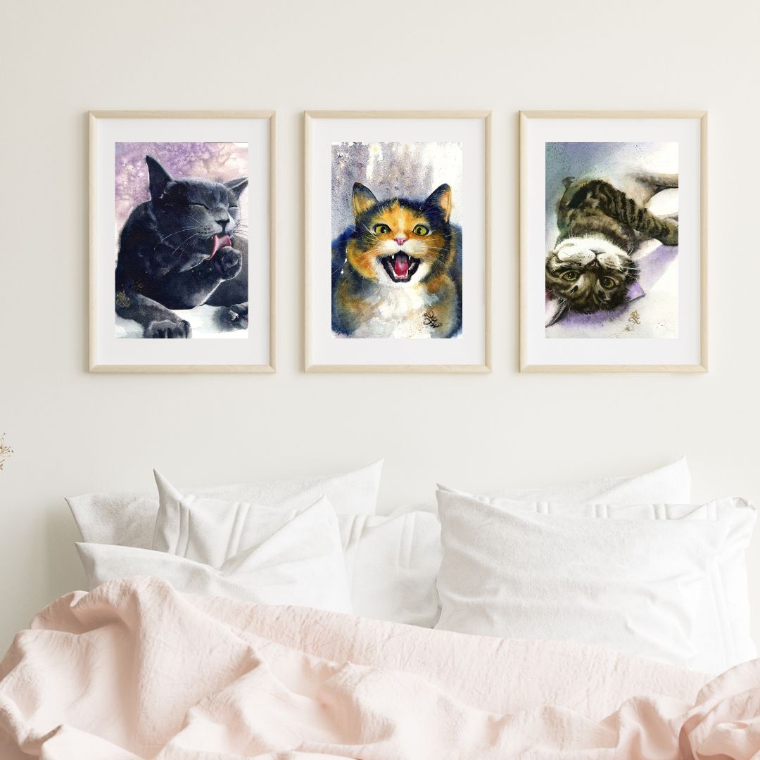 Three framed paintings of cats on a wall above a bed. Watercolor painting by Sophie Xie Dream In Watercolor. This stunning painting is available as a print on my website, http://www.dreaminwatercolor.com