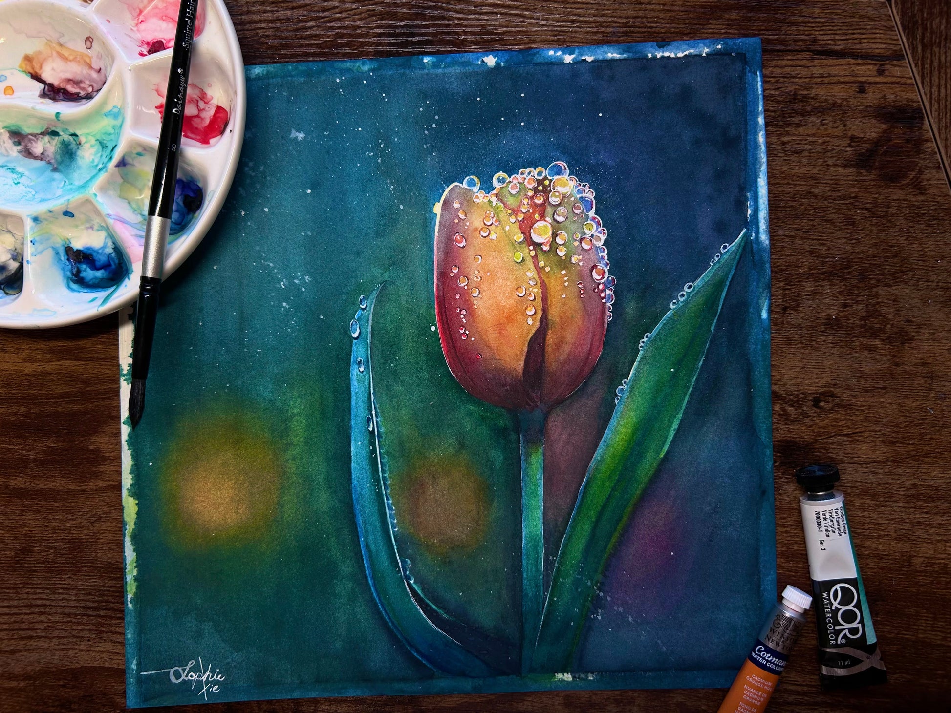 The artwork titled "Tulip" beautifully captures a half-bloomed tulip, its delicate petals unfolding gracefully. The flower is adorned with shimmering raindrops that cling to its surface, reflecting light and creating a sparkling effect that enhances the vibrant hues of the petals. The scene evokes a sense of freshness and vitality, celebrating the beauty of nature in a single moment.