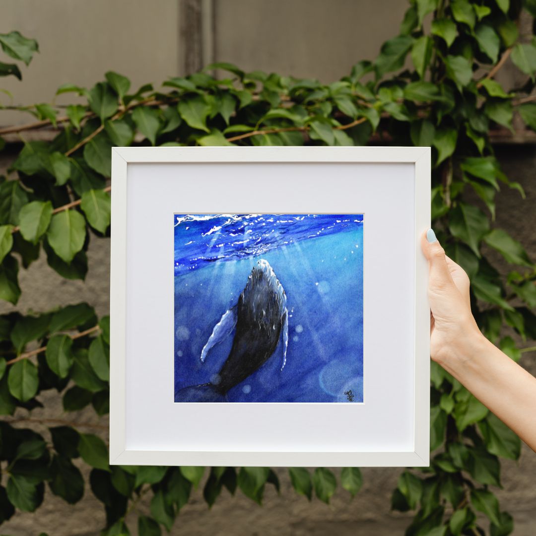 The artwork titled "Whale" vividly illustrates a majestic whale gracefully interacting with the shimmering light that dances across the ocean's surface. The waves gently ripple around it, enhancing the serene and magical atmosphere of this aquatic moment.